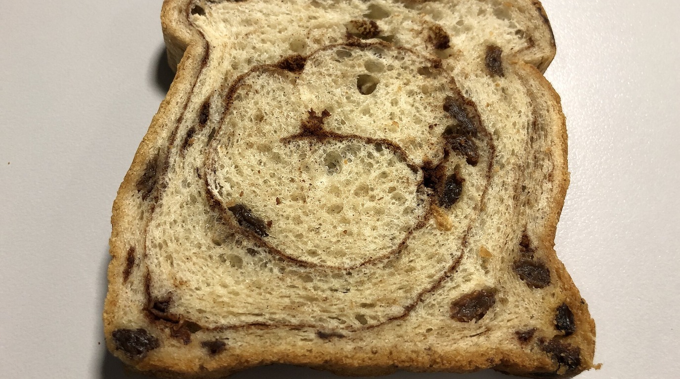 Sliced cinnamon raisin bread loaf showing plump dark raisins and cinnamon swirl