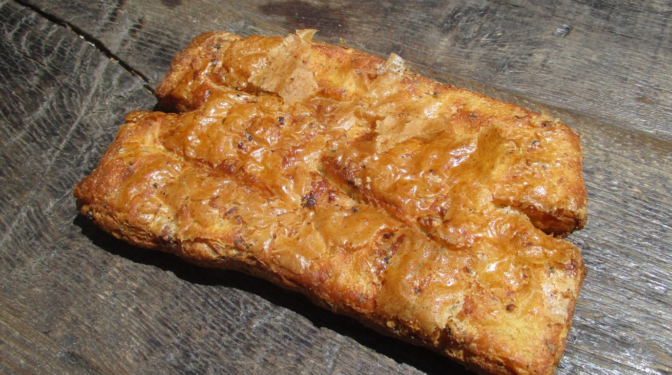 Golden Mediterranean olive sourdough bread loaf resting on a rustic dark wooden table