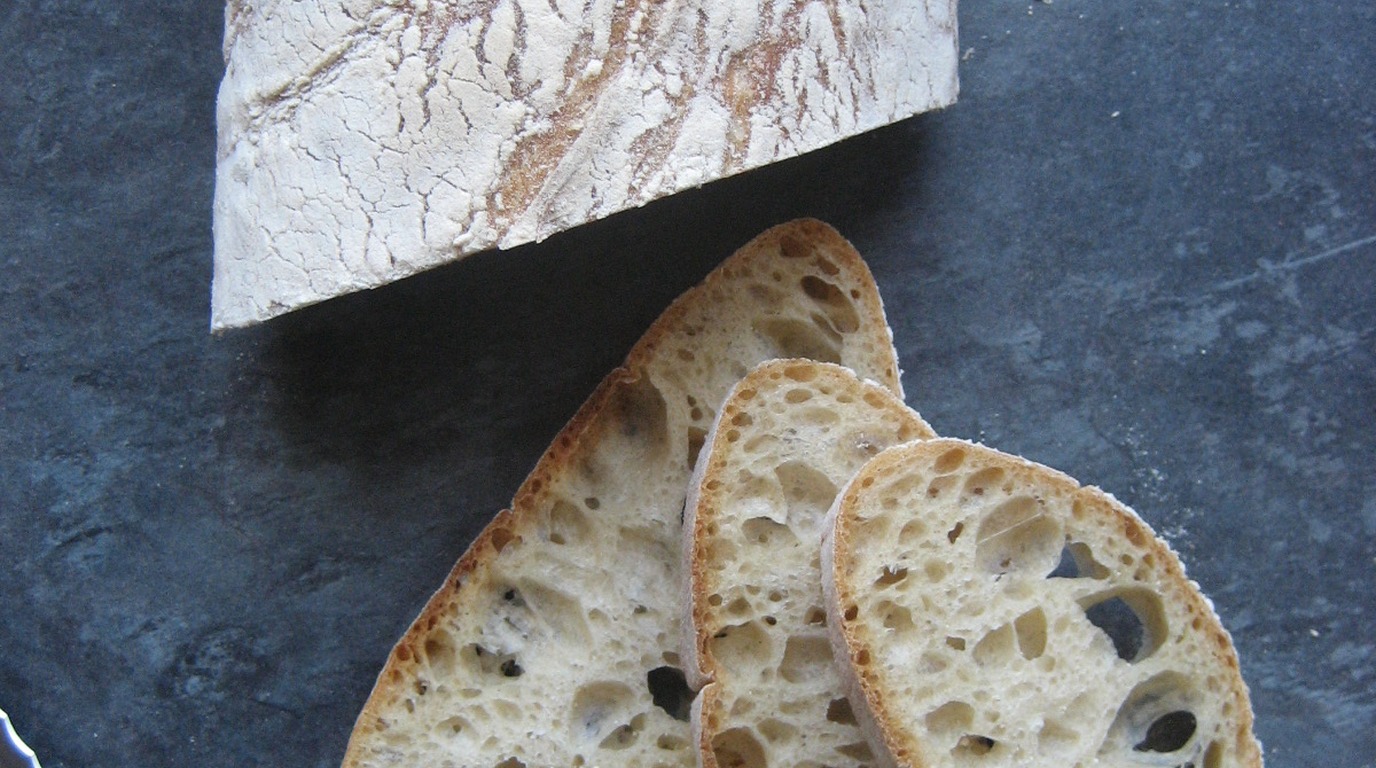 Rustic Italian ciabatta bread loaves with flour-dusted crisp crust and irregular open interior alveoli