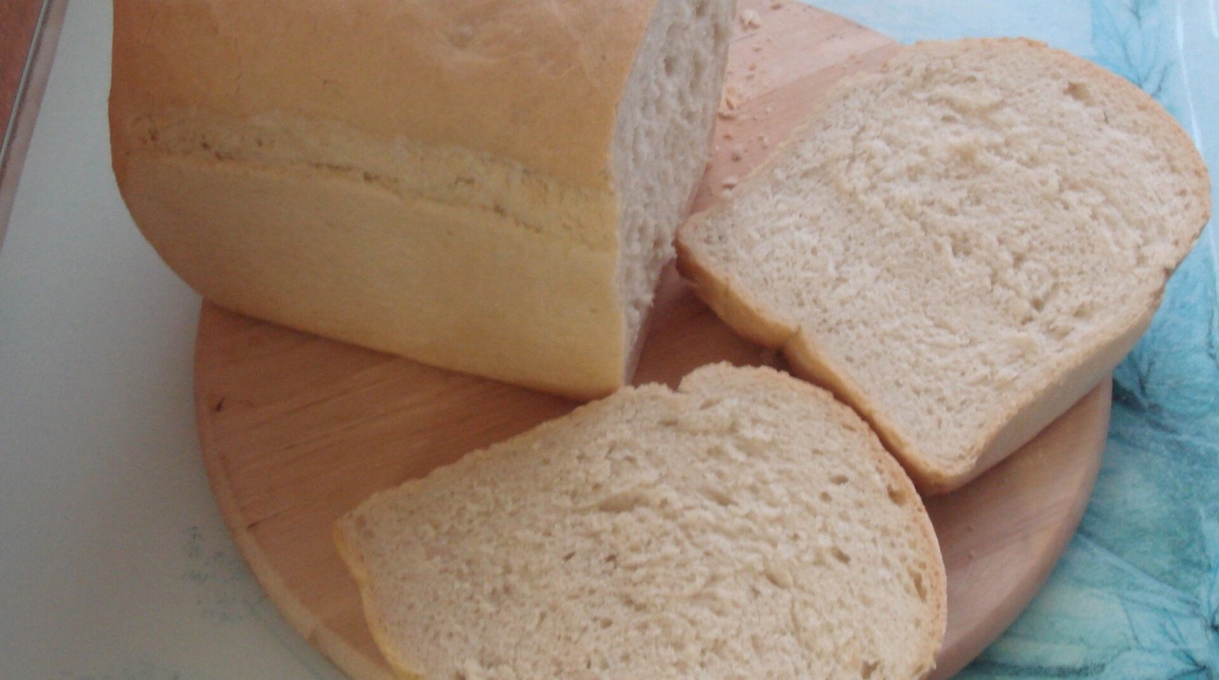 Golden pan-baked sourdough sandwich bread loaf sliced into uniform soft square toast slices